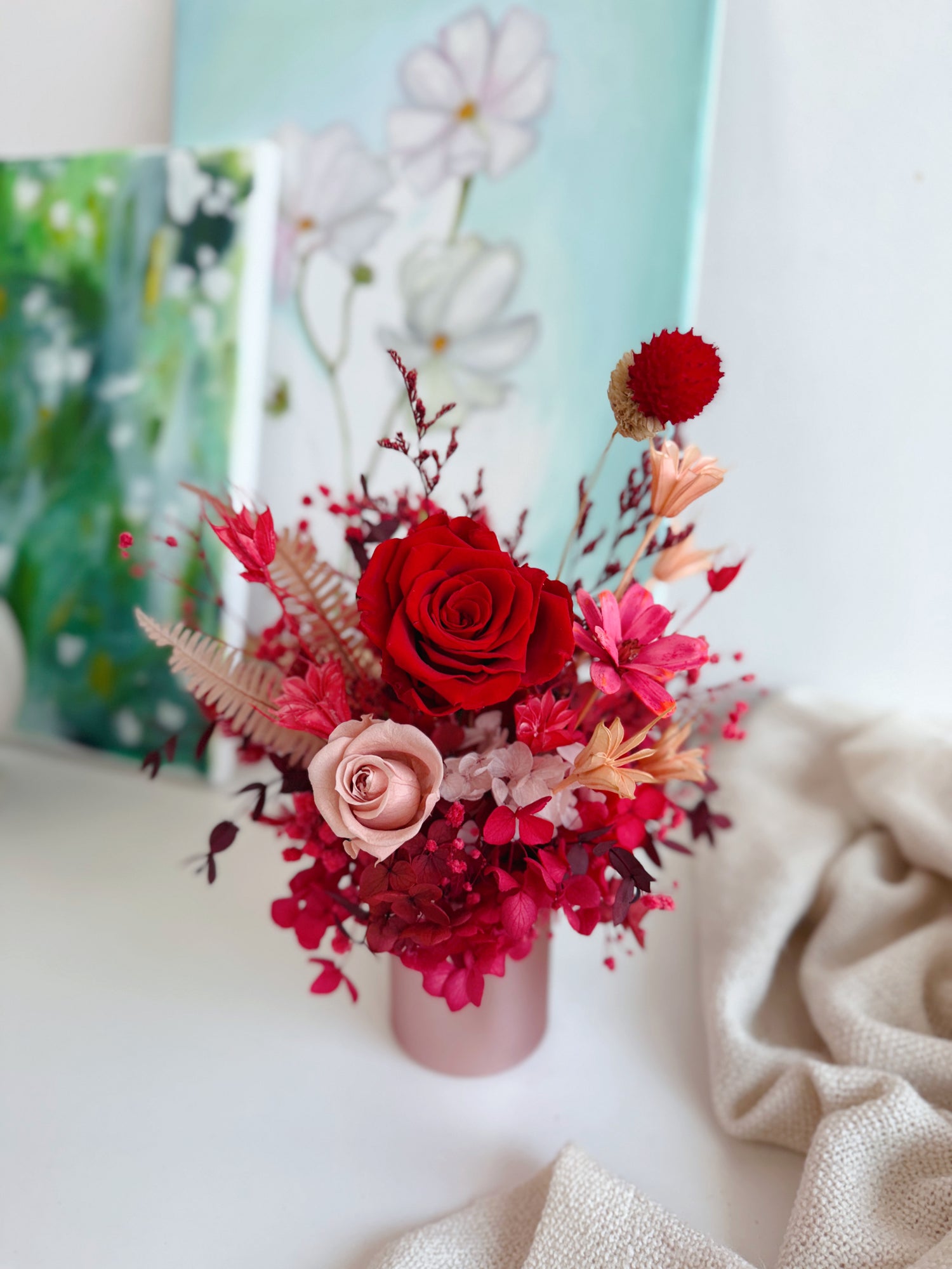 Bouquet of red and pink flowers in a bloom box on a light surface with a blurred background