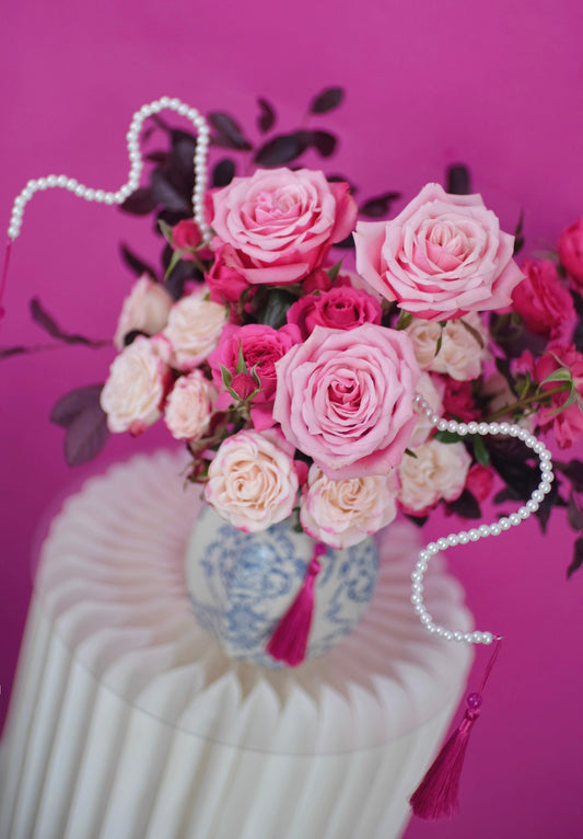 CNY floral arrangement features delicate pink roses and spray roses with deep burgundy accents and snake-like pearls in china porcelain vase