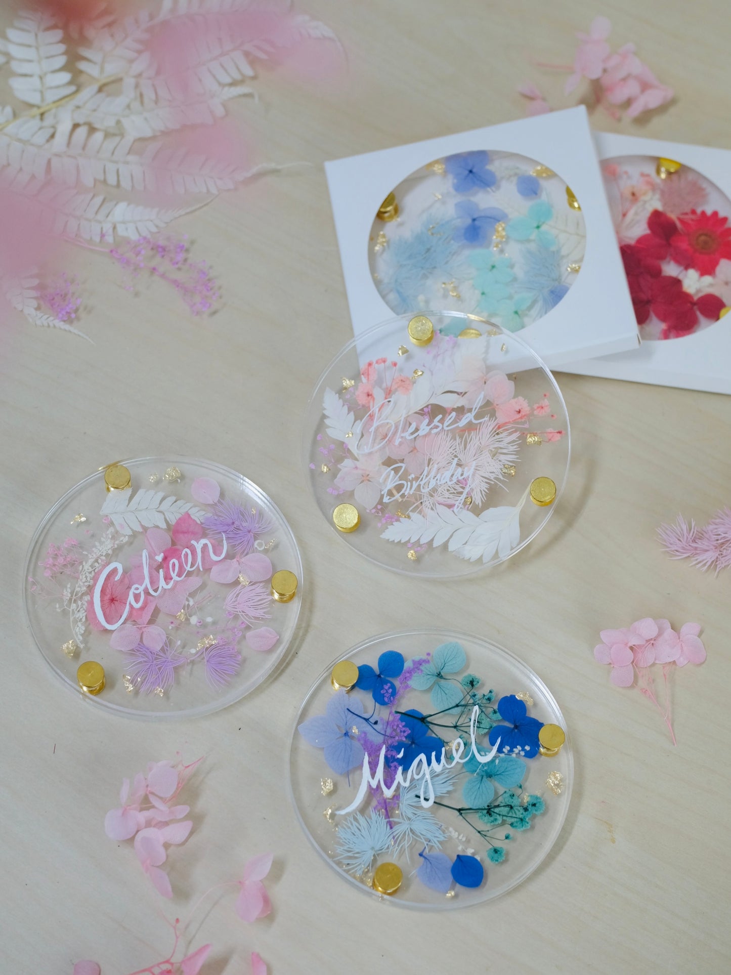 Decorative coasters with floral designs and names on a floral background