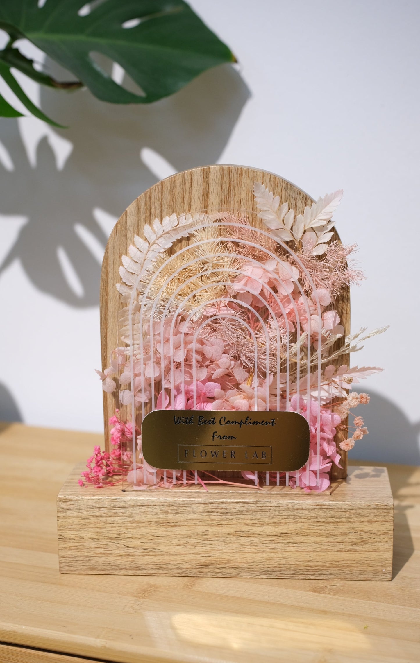 Decorative trophy with pink and gold design on a wooden surface