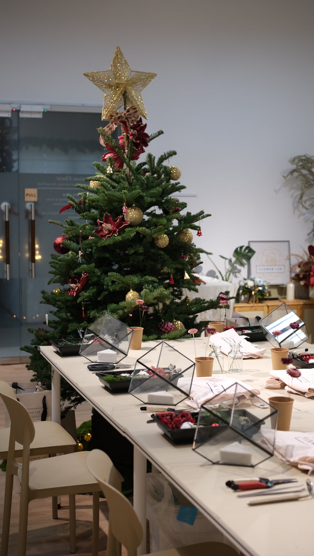 Flower Lab studio set for a Christmas workshop, with a long table in front of a decorated tree