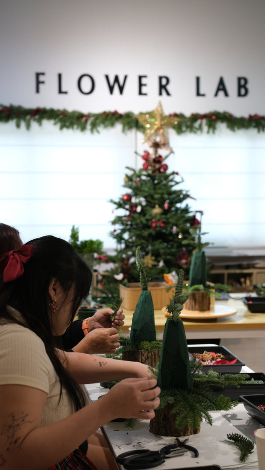 Participants making fresh tabletop Christmas trees at the studio table